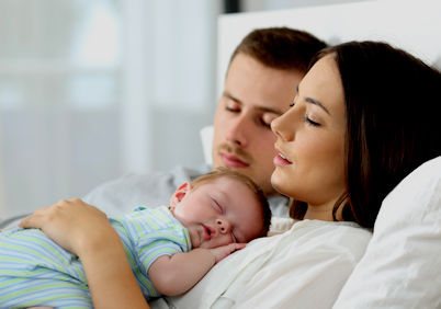 Couple in bed with newborn child